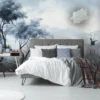 Modern bedroom with a gray upholstered bed against a Verdant Valley Blooms Mural (Copy), featuring a serene landscape with trees and mountains. The bed has white and gray bedding and a plaid throw. A desk with a chair, potted plant, and side tables with lamps complement the decor.
